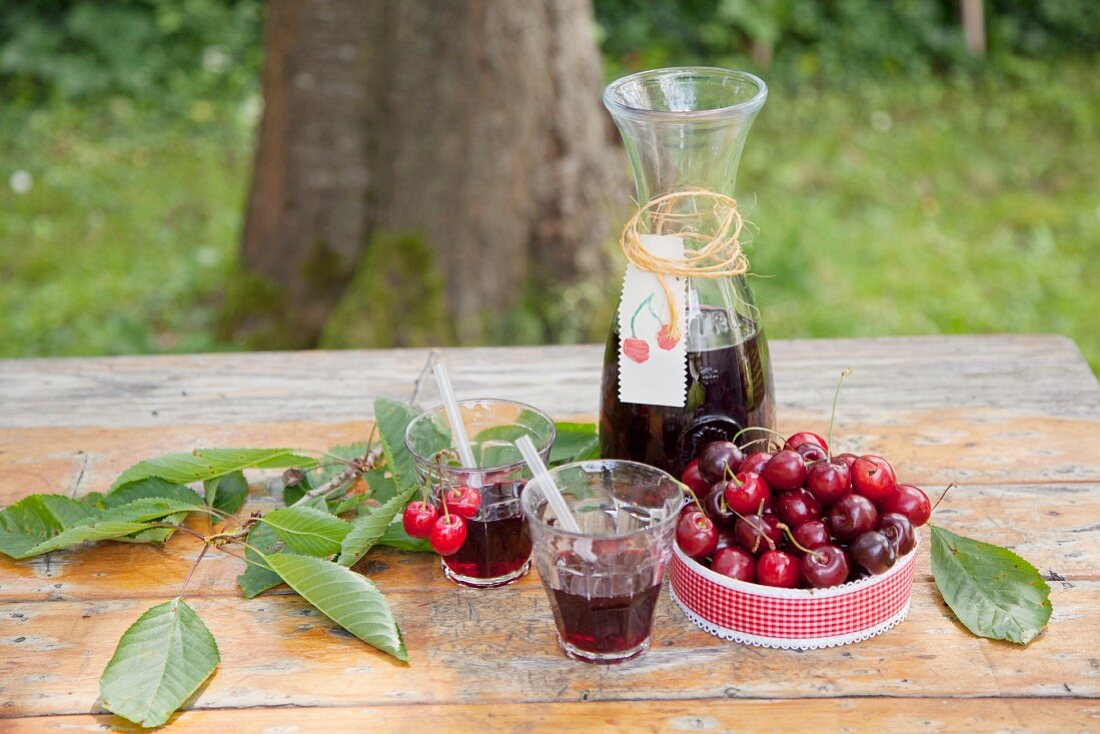 Karaffe und Gläser mit Saft, eine Schale mit Kirschen