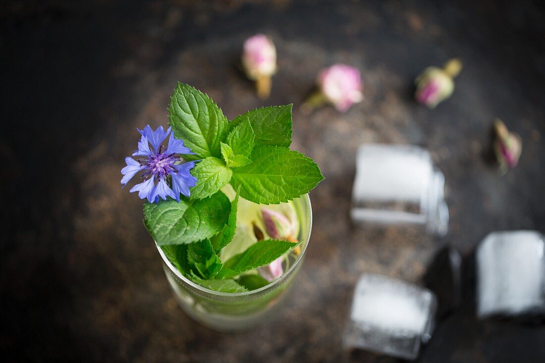 Iced tea with fresh mint, ice cubes, dried roses and cornflowers