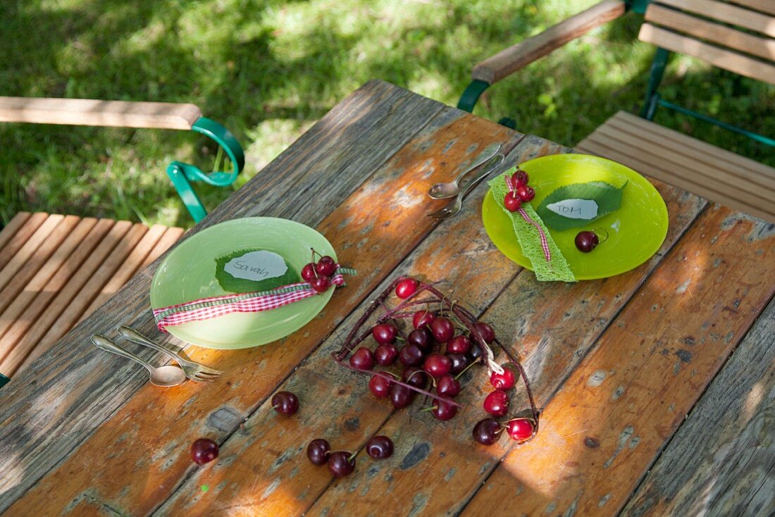 Gartentisch mit grünen Tellern und Kirschen