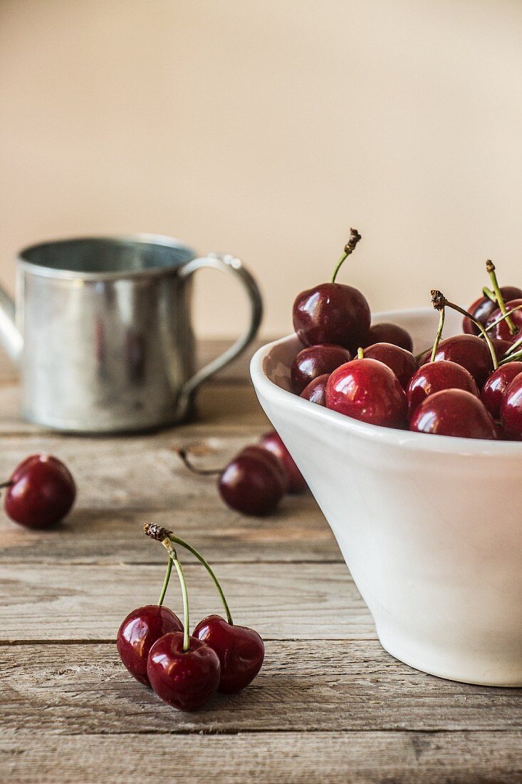Cherries in a white ceramic bowl on a wooden table