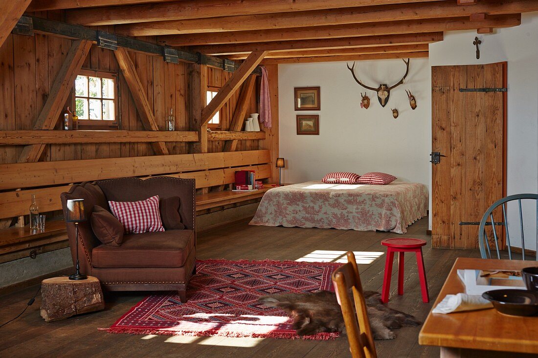 Open-plan interior with seating and double bed in rustic wooden house