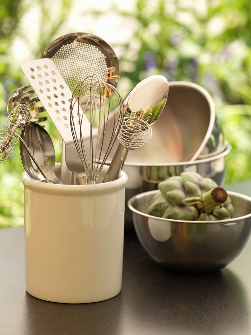 Kitchen utensils and artichokes in a stainless steel