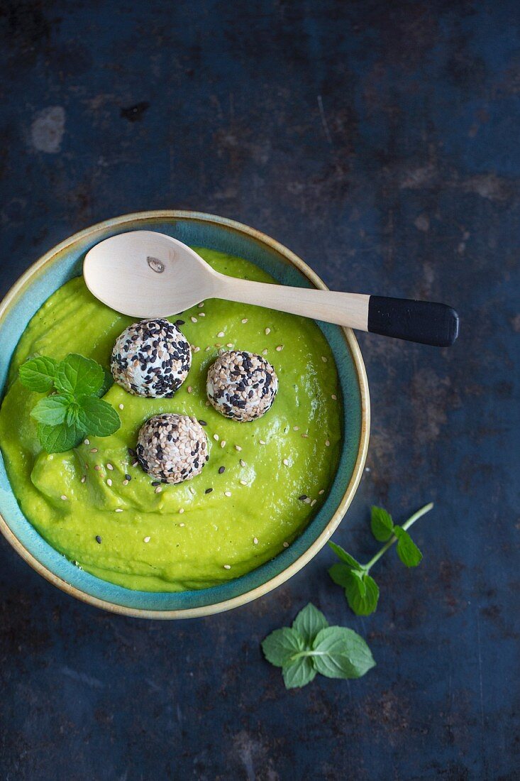 Pea soup with mint leaves and feta cheese balls rolled in sesame seeds