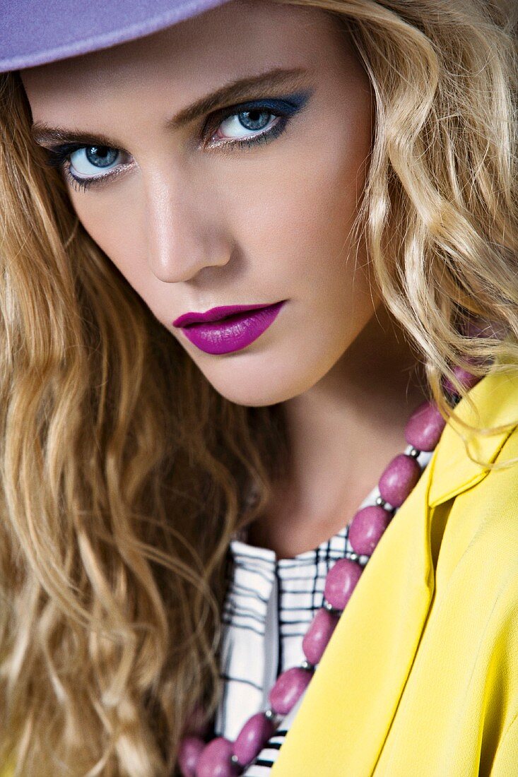 Blonde woman wearing a jacket and hat in yellow and purple