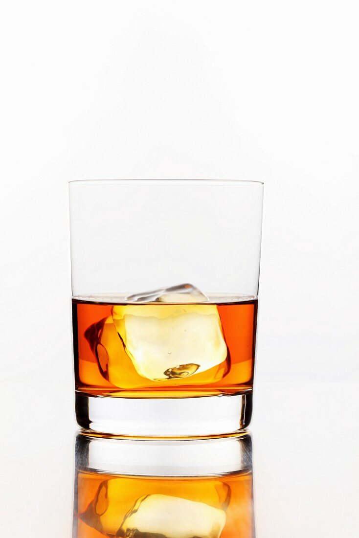 A glass of whiskey with an ice cube