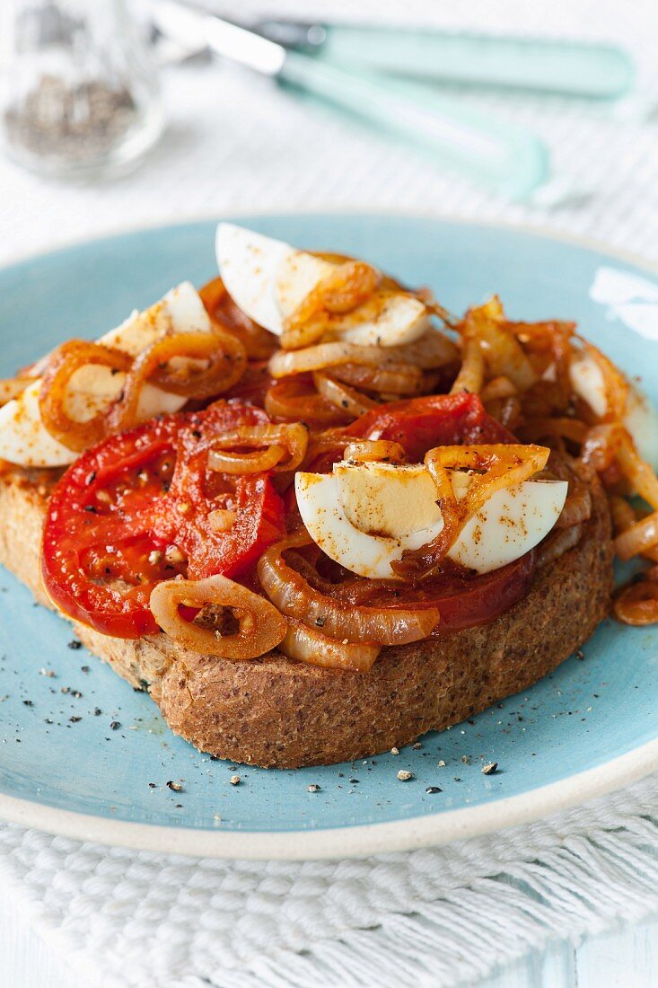 Toast topped with egg, onions, tomatoes and paprika
