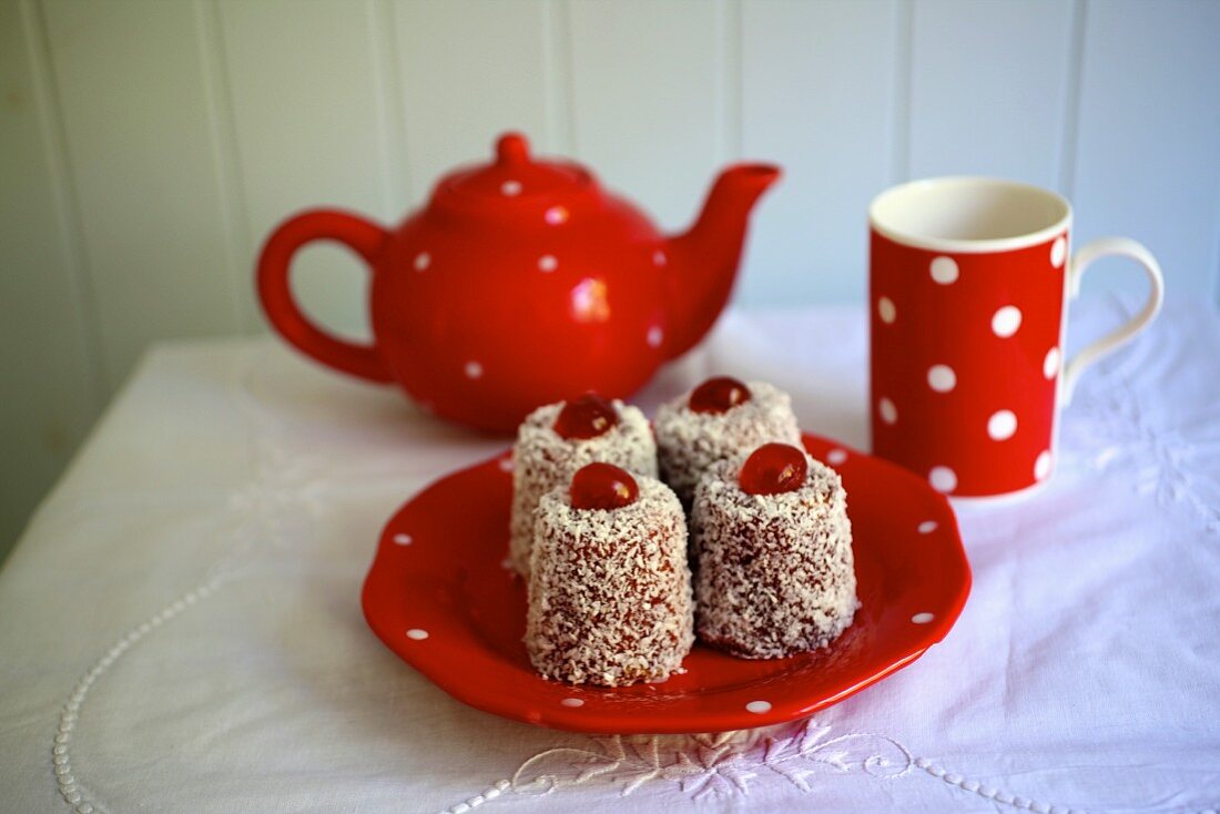 Englische Madeleines mit Himbeermarmelade und Kokosraspeln vor Teegeschirr