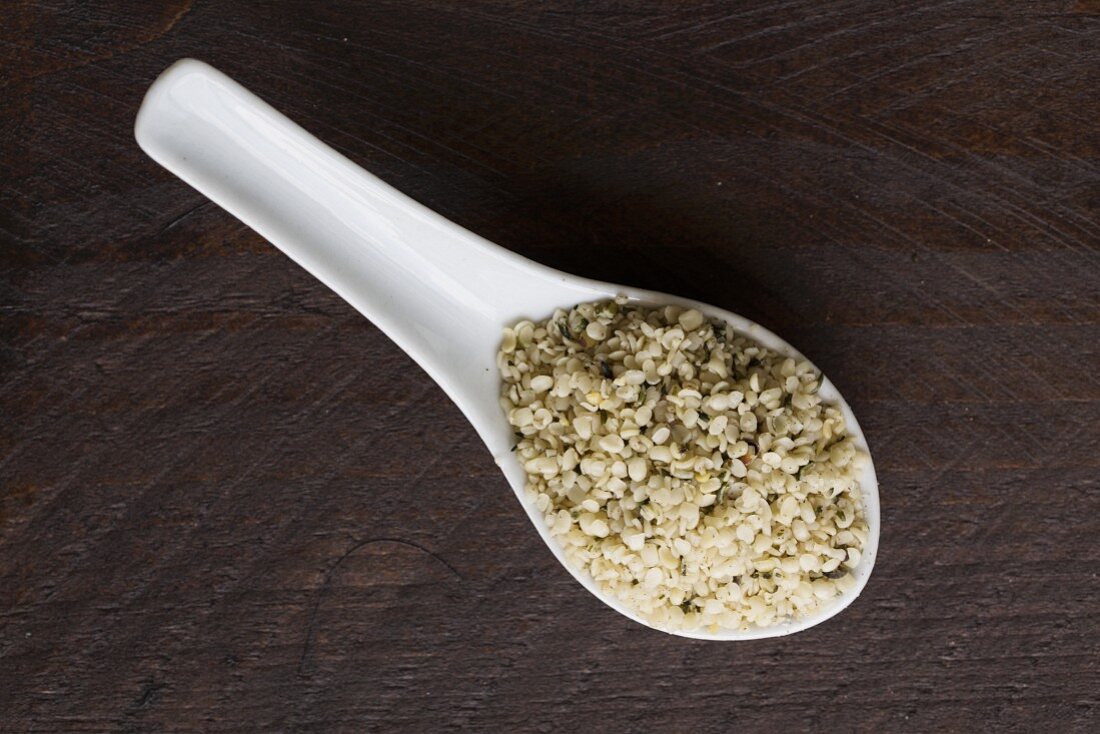 Hemp seeds on a porcelain spoon on a dark surface
