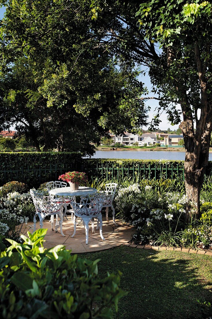 Idyllischer Gartenplatz mit weißen nostalgischen Metallstühlen und romantischem Flair