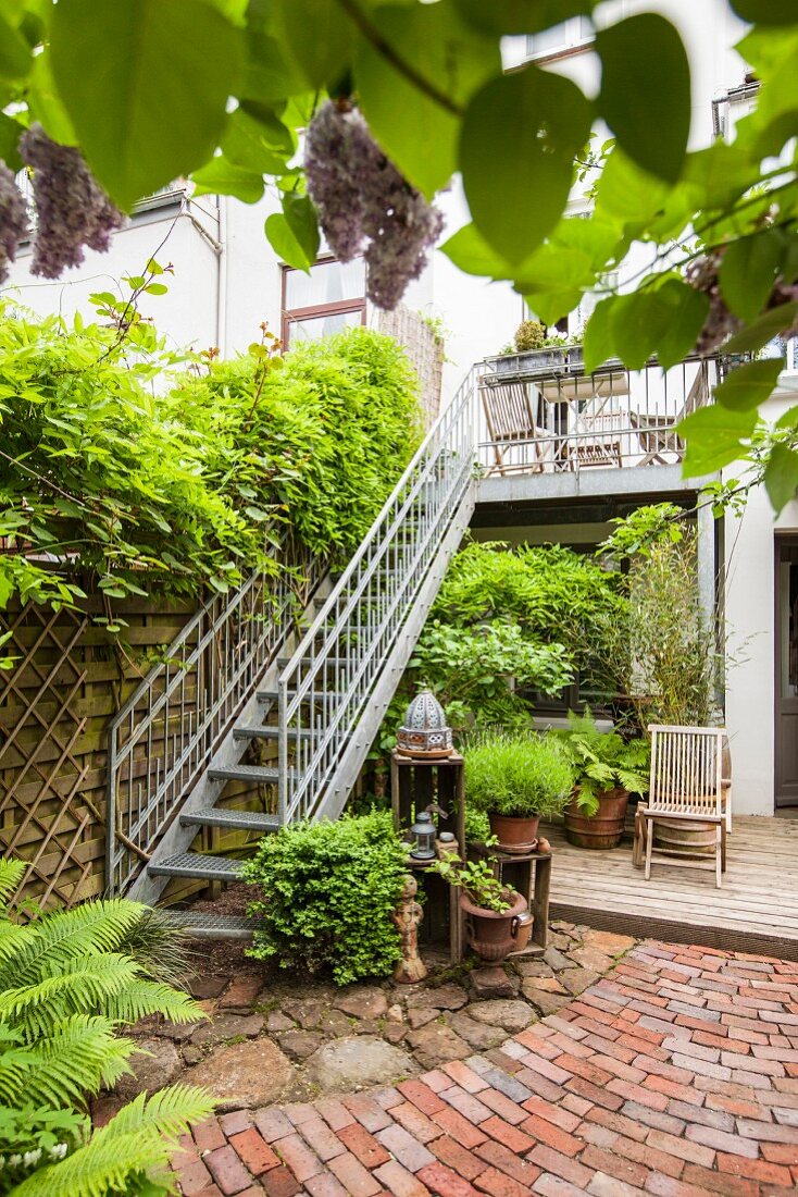 Begrünter Terrassenplatz mit verzinkter Balkon-Außentreppe und Topfpflanzen auf Natursteinboden