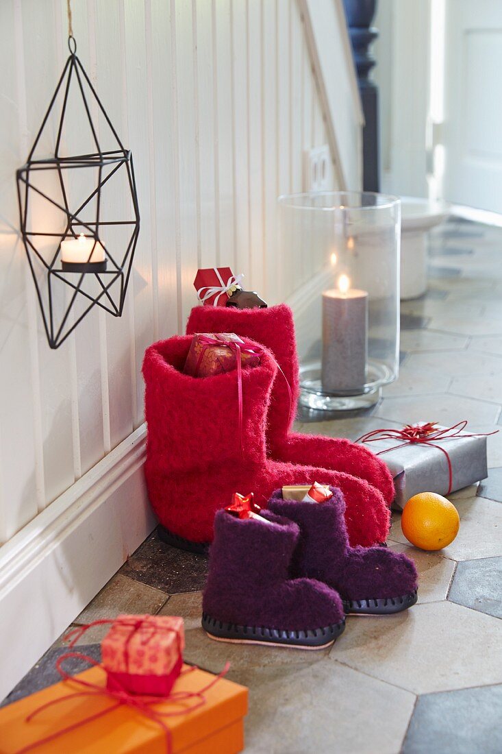 Selbstgenähte Nikolausstiefel aus flauschigem Wollstoff und Hüttenschuhsohlen, Kerzenhalter und Geschenkpäckchen auf dem Boden