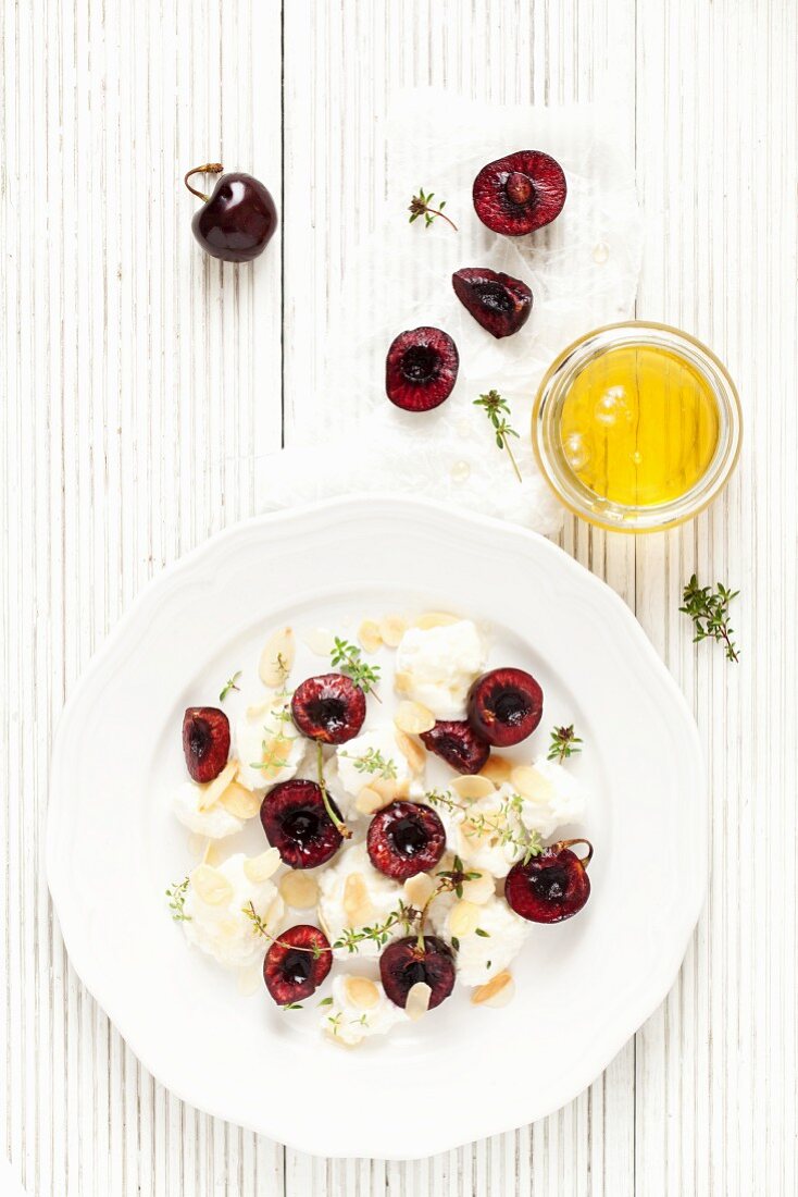 A plate of ricotta with fresh cherries, almonds, thyme and honey