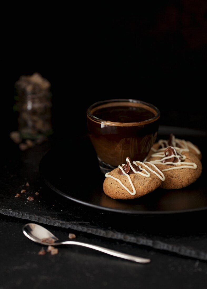 Three hazelnut cookies filled with ganache on a plate with a cup of coffee