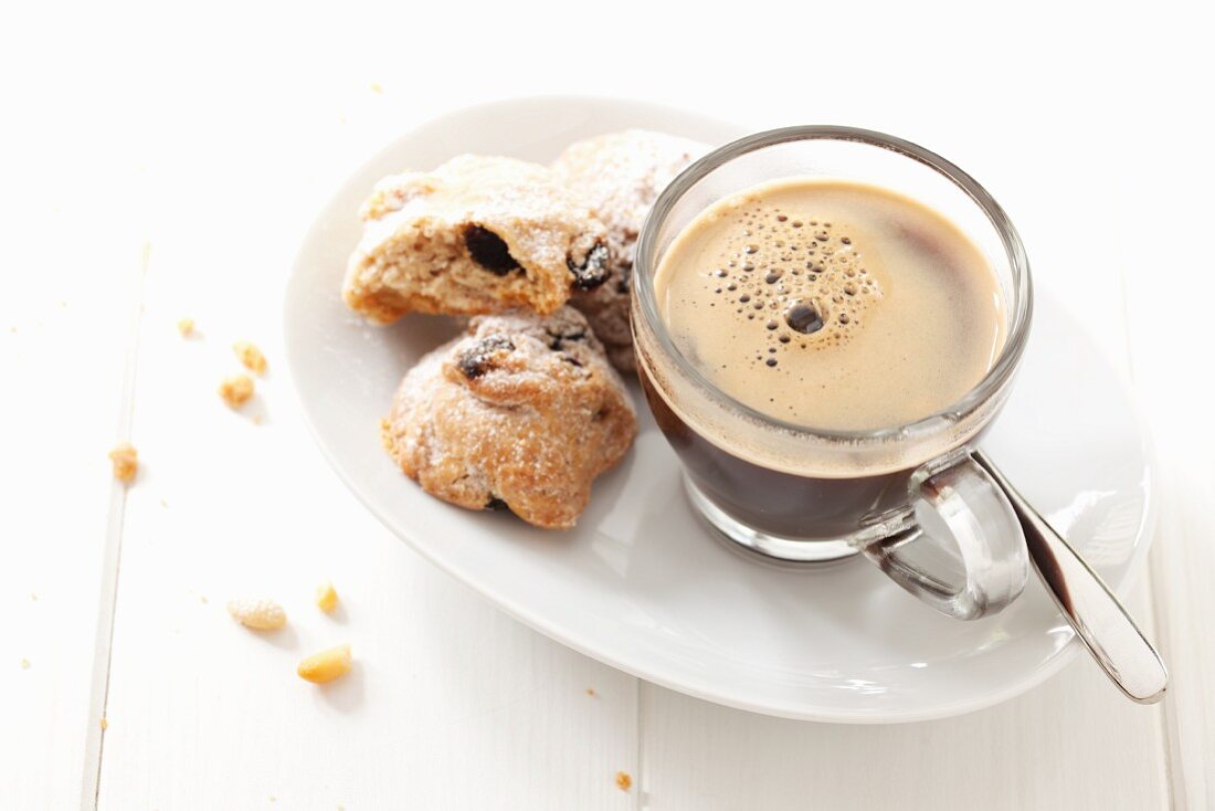 Black coffee in a glass cup on a saucer served with pine nut biscuits (Italy)