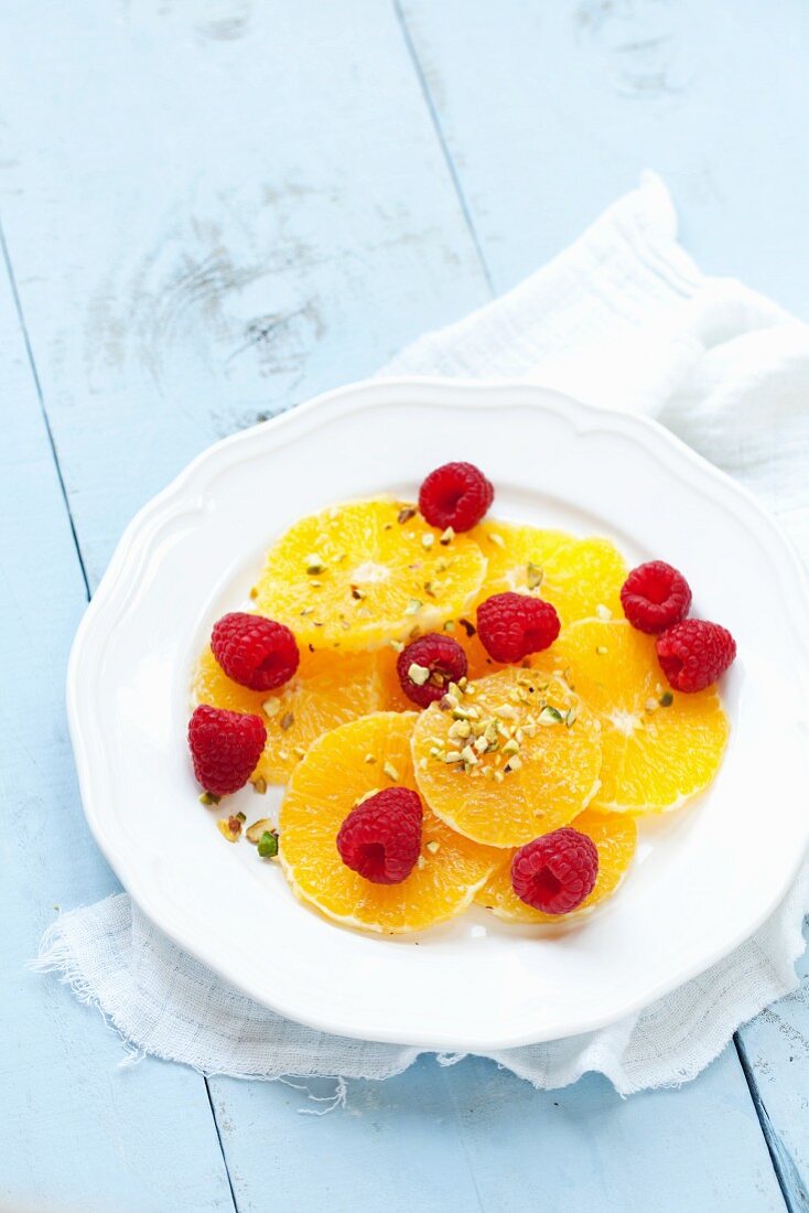 Orangenscheiben mit Himbeeren und gehackten Pistazien