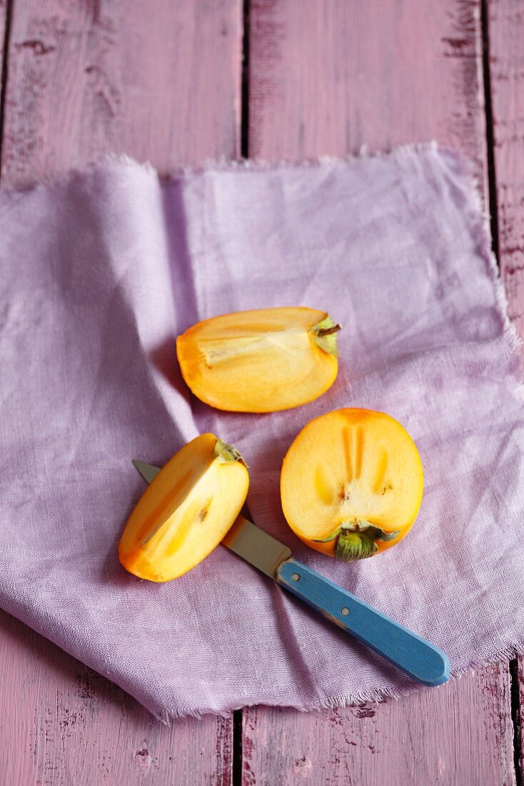 Persimmons, sliced, on a purple cloth
