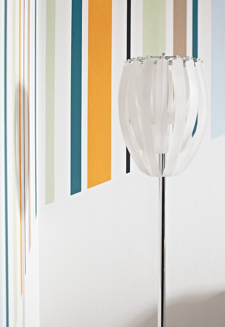 Standard lamp in front of multicoloured striped area on wall (detail)