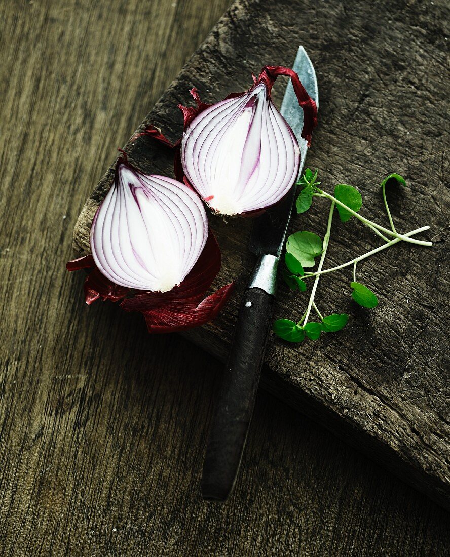 A halved red onion on a wooden chopping board