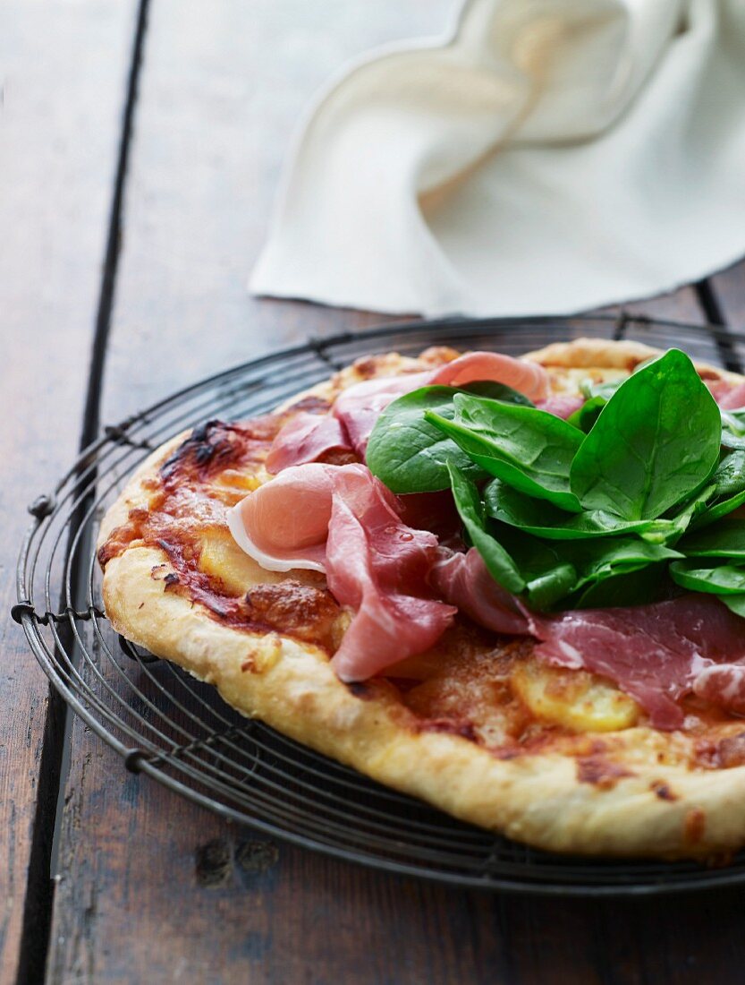 Pizza with potatoes, raw ham and spinach