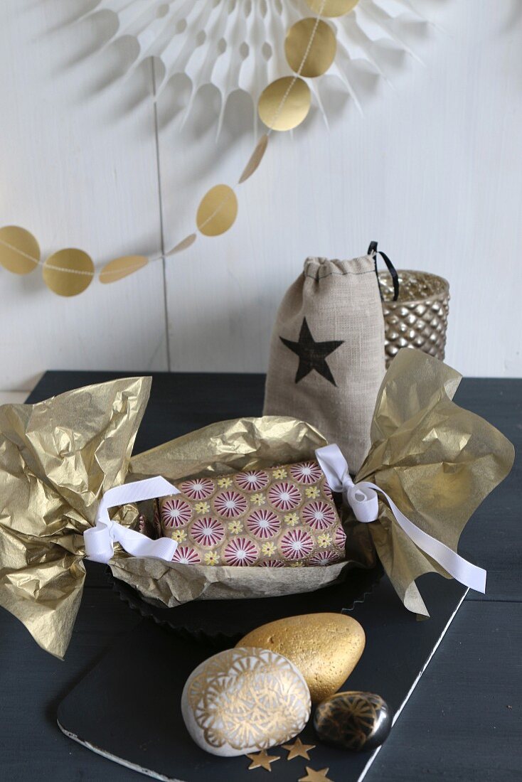 Christmas present wrapped in gold paper and gold-painted pebbles