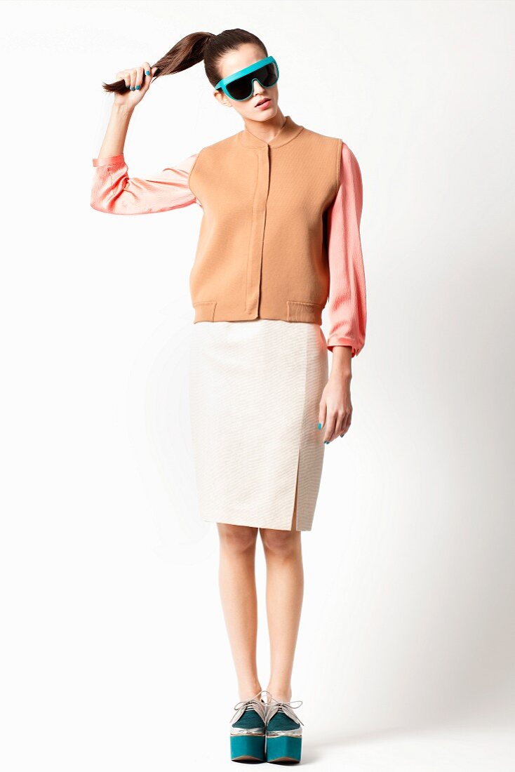 A young woman wearing a blouse, a gilet, a pencil skirt and platform shoes