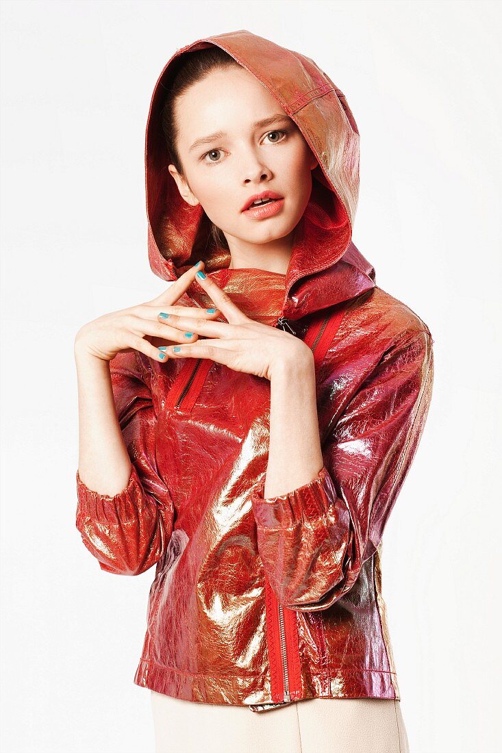A young woman wearing a shiny red leather jacket with a hood