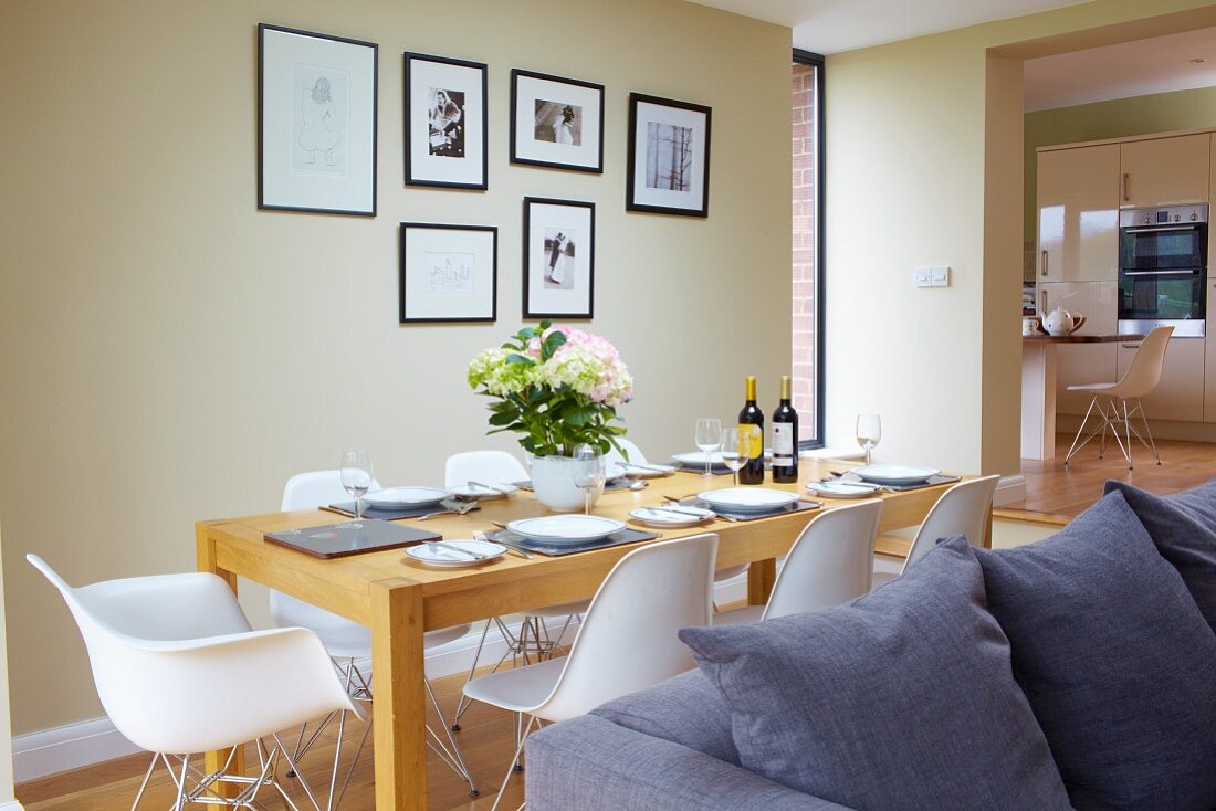 White classic shell chairs at set table in open-plan interior with walls painted pastel green