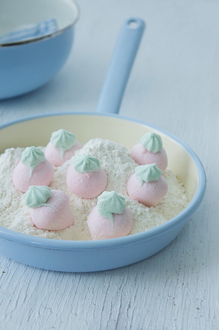 Strawberry-shaped marshmallows with icing sugar in a frying pan