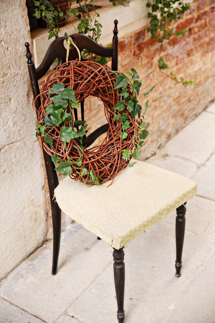 Weidekranz mit Efeu auf einem Stuhl vor Backsteinmauer