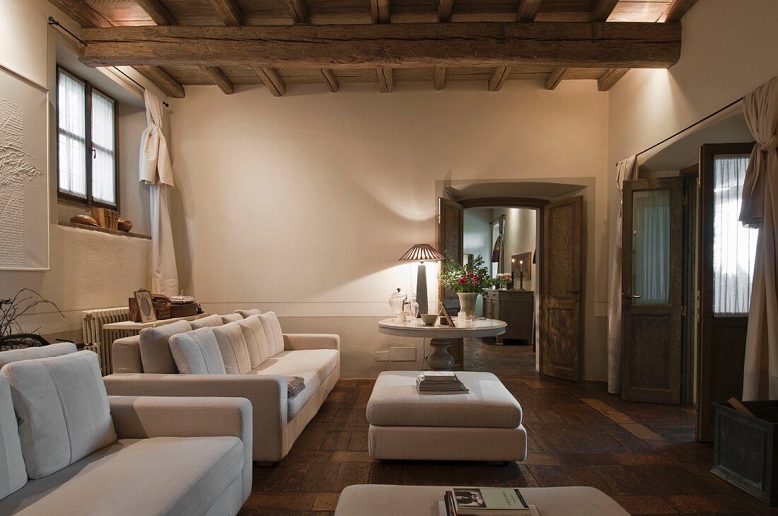 Elegant white sofa set and matching ottomans in renovated rustic living room