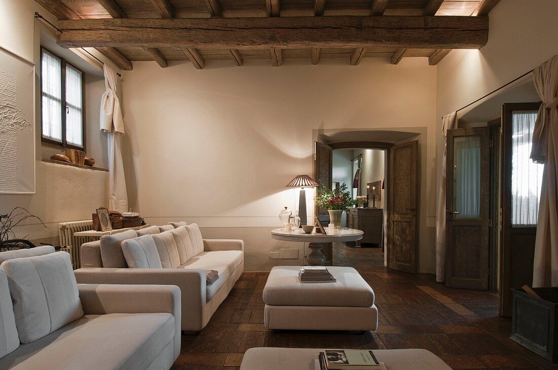 Elegante, weiße Sofagarnitur und passende Couchtische in renoviertem, rustikalem Wohnzimmer