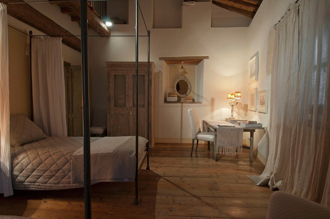 Canopy bed with minimalist metal frame and illuminated study area in simple bedroom