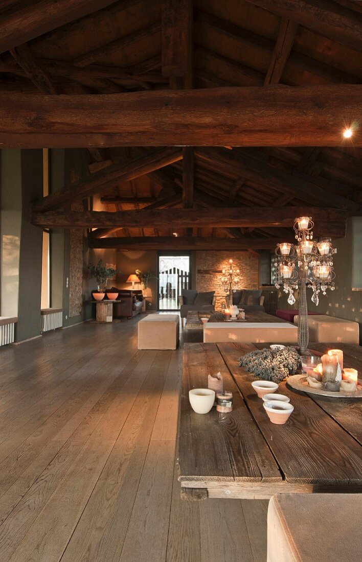 Interior with exposed wooden roof structure, coffee table with board top and upholstered benches