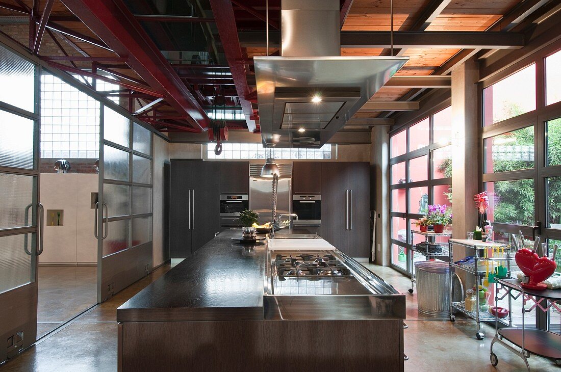 Modern designer kitchen in loft apartment with island counter, fitted appliances in background and view into hall