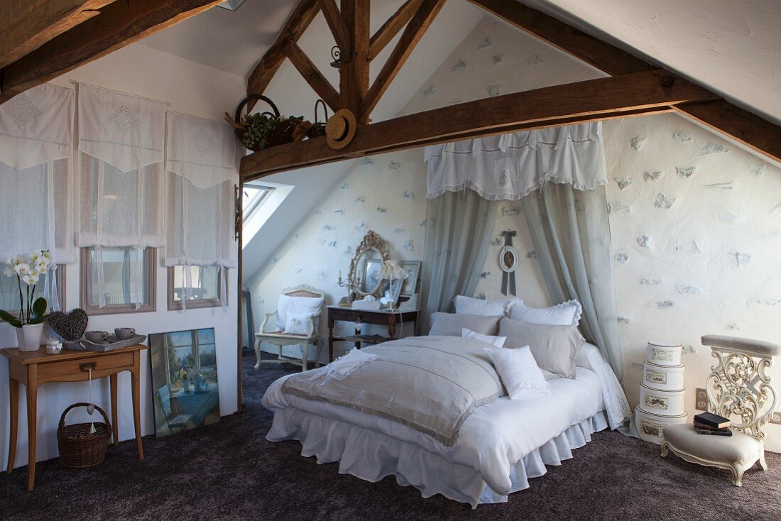 Lace-edged pillows on double bed with pelmet and curtains in romantic attic bedroom