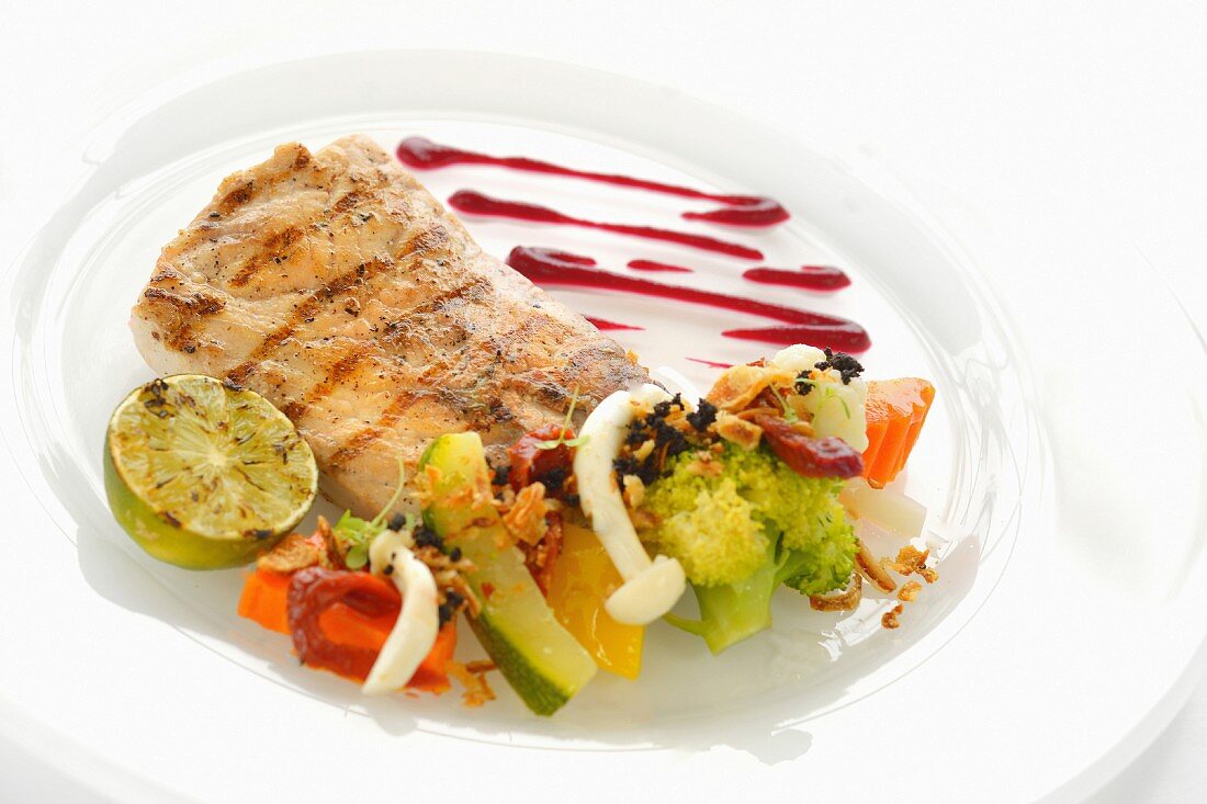 Grilled fish fillet with a vegetable salad, chilli sauce and lime