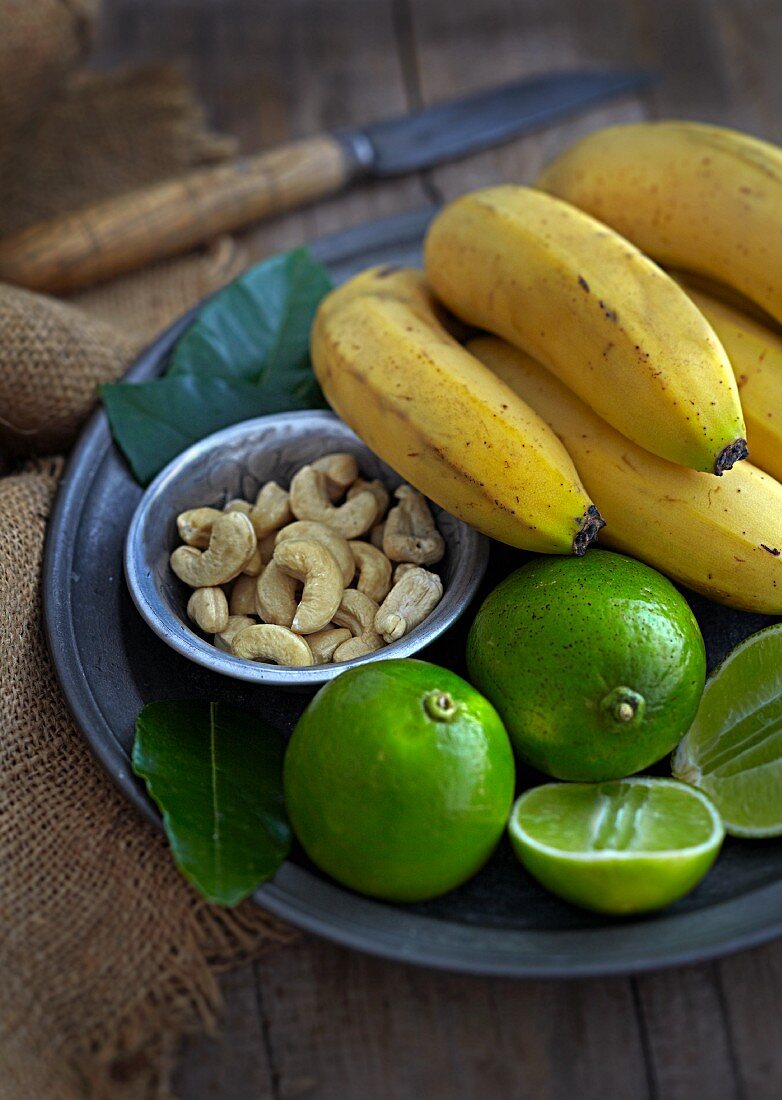Exotisches Stillleben mit Bananen, Limetten und Cashewkernen