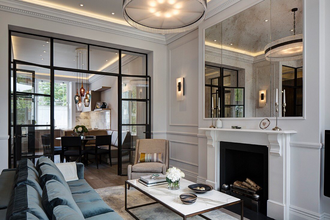 Coffee table in front of open fireplace, glass partition with open door and view into dining room