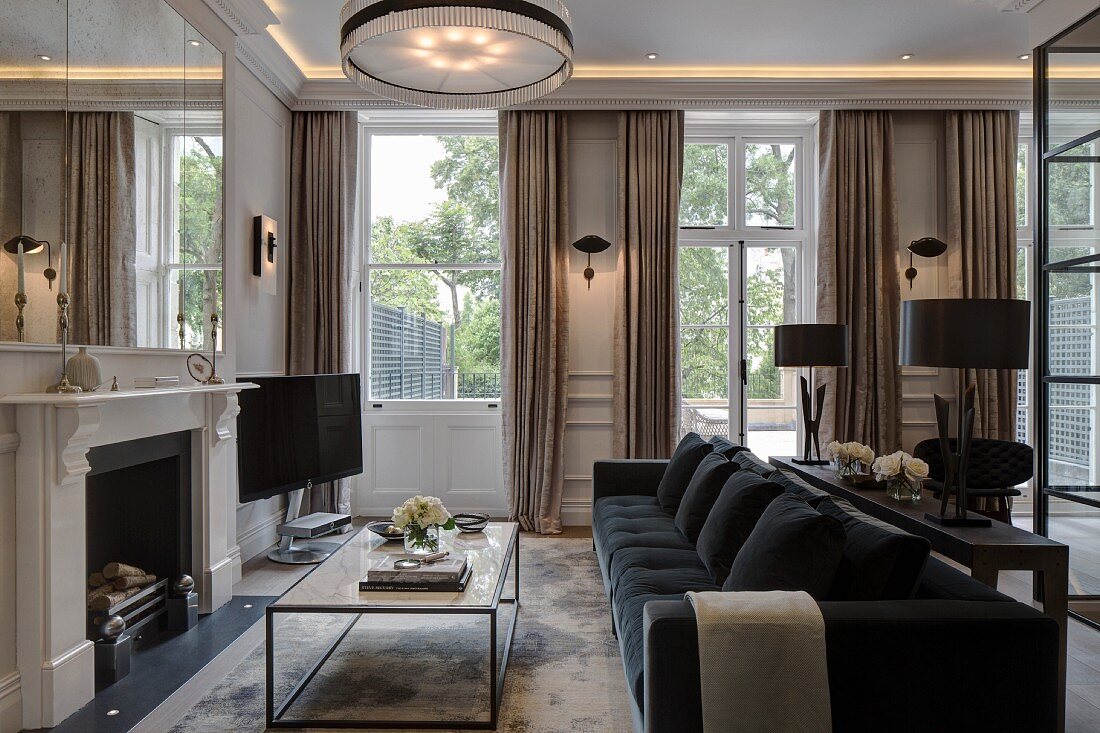 Coffee table in front of open fireplace; floor-length curtains on French windows