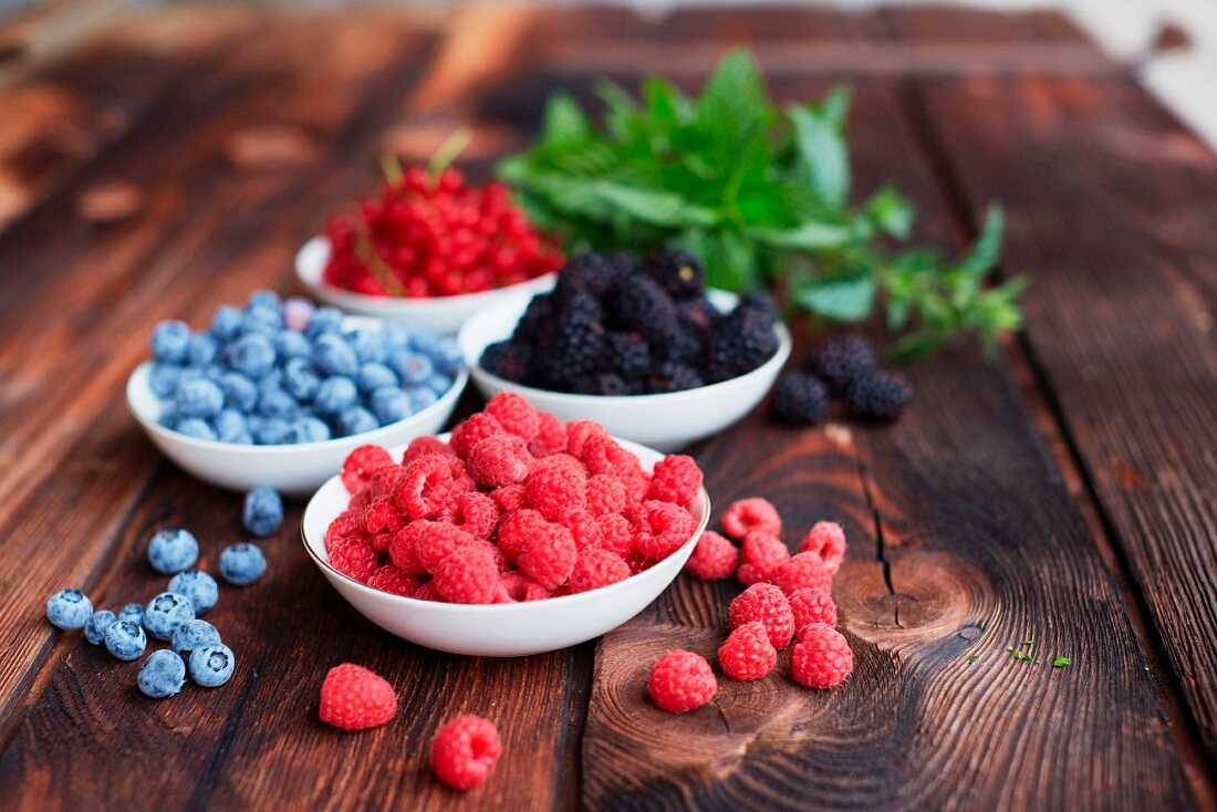 Four bowls of fresh berries on a picnic table