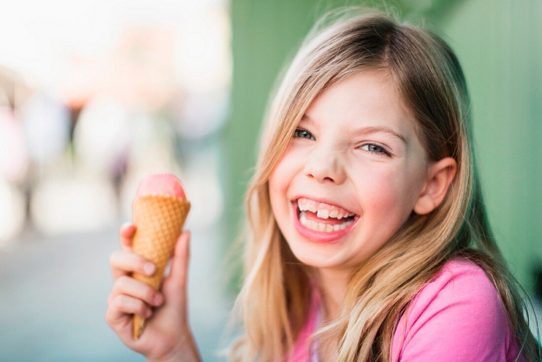 A little blonde girl eating an ice cream