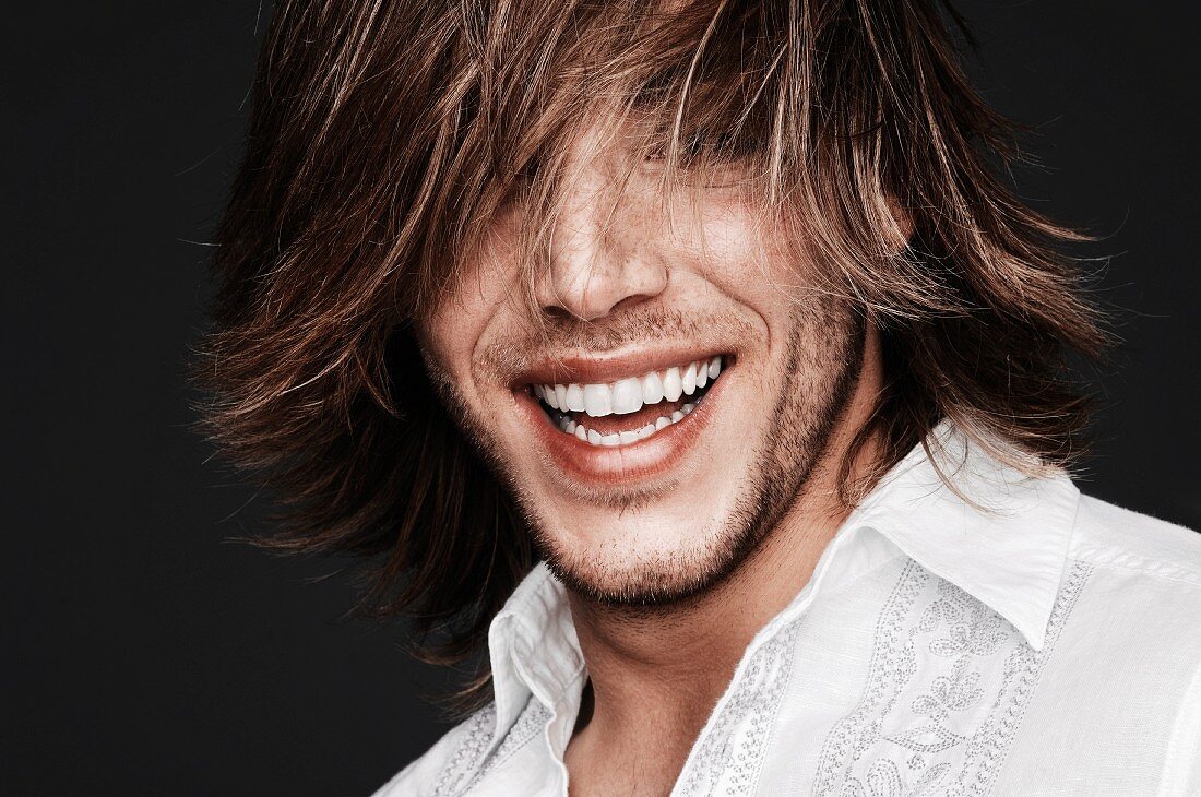 A laughing young man with his hair over his eyes