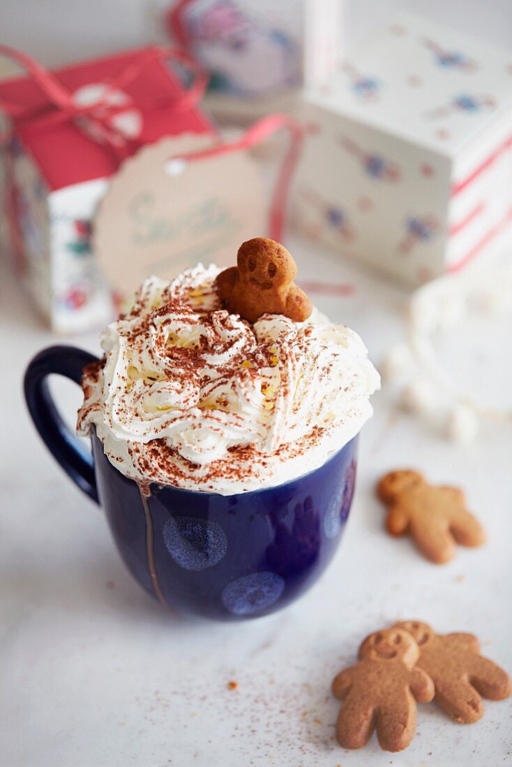 Hot chocolate topped with cream and gingerbread biscuits
