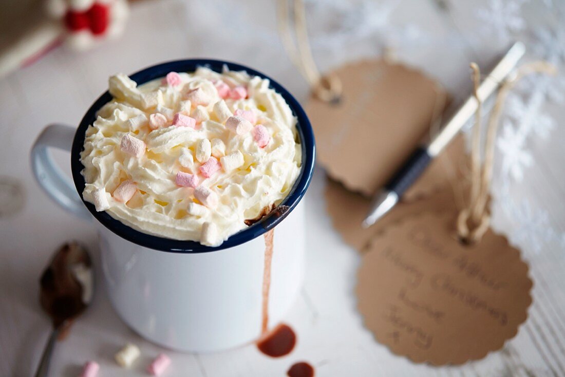 Hot chocolate in an enamel mug with cream and marshmallows