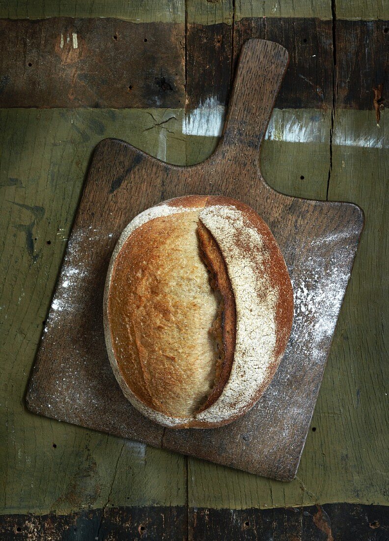A loaf of country bread on a chopping board (seen from above)