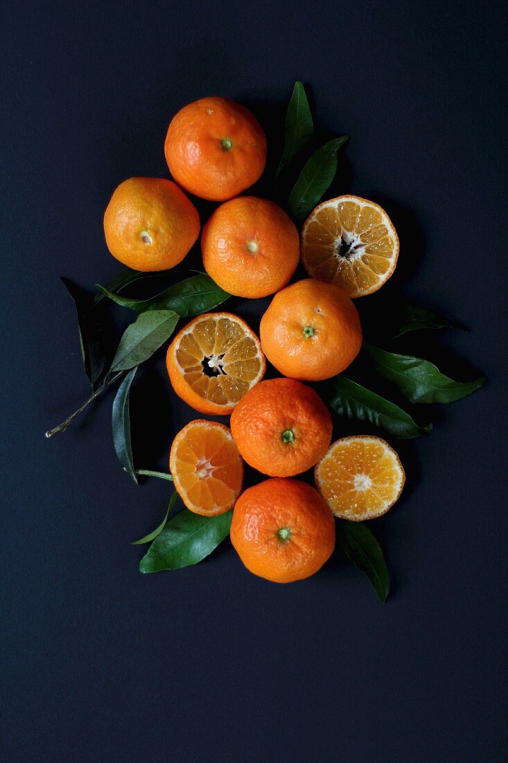 Mandarins and mandarin leaves on a blue surface