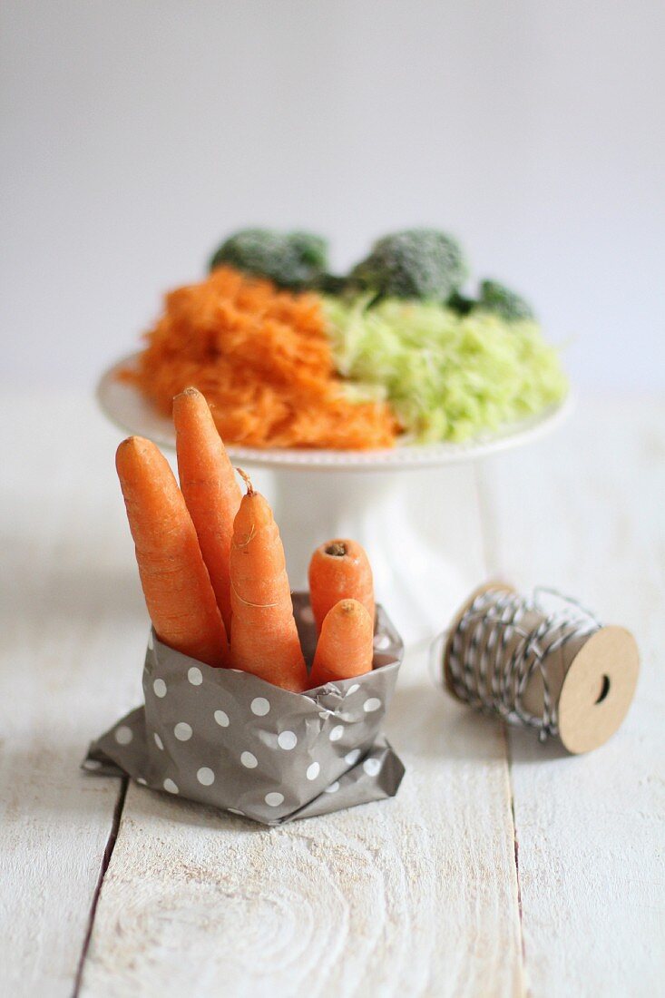 Carrots in a paper bag with a pile of grated vegetables in the background