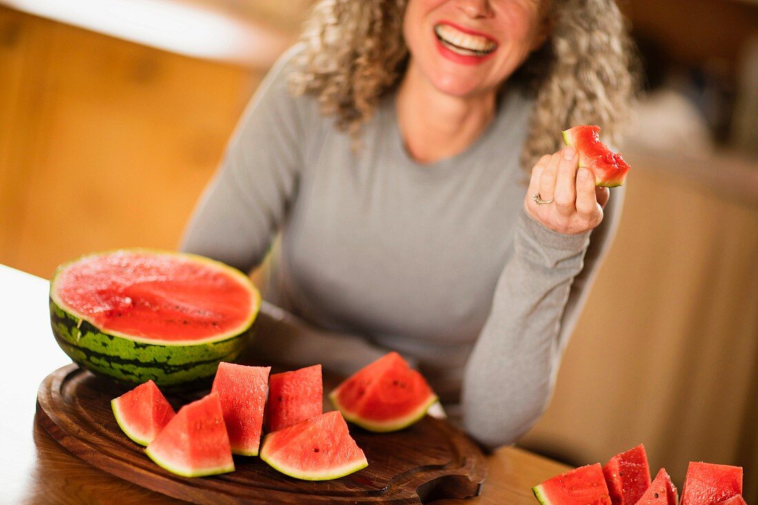 A woman eating a watermelon by the sea in the archipelago of Stockholm, Sweden.