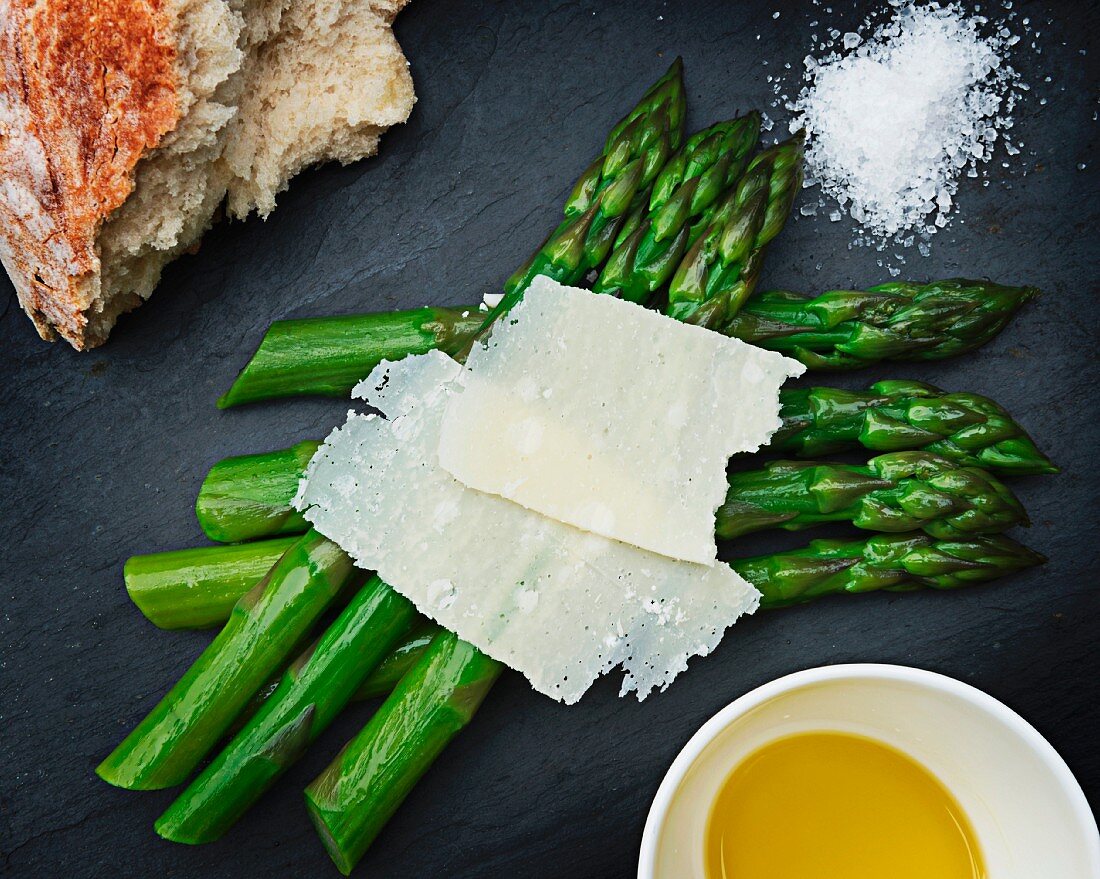 Green asparagus with shaved cheese, melted butter, sea salt and bread (seen from above)