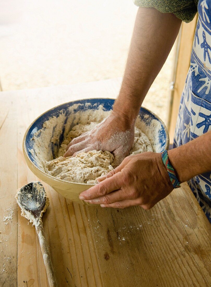A person kneading a bowl of dough